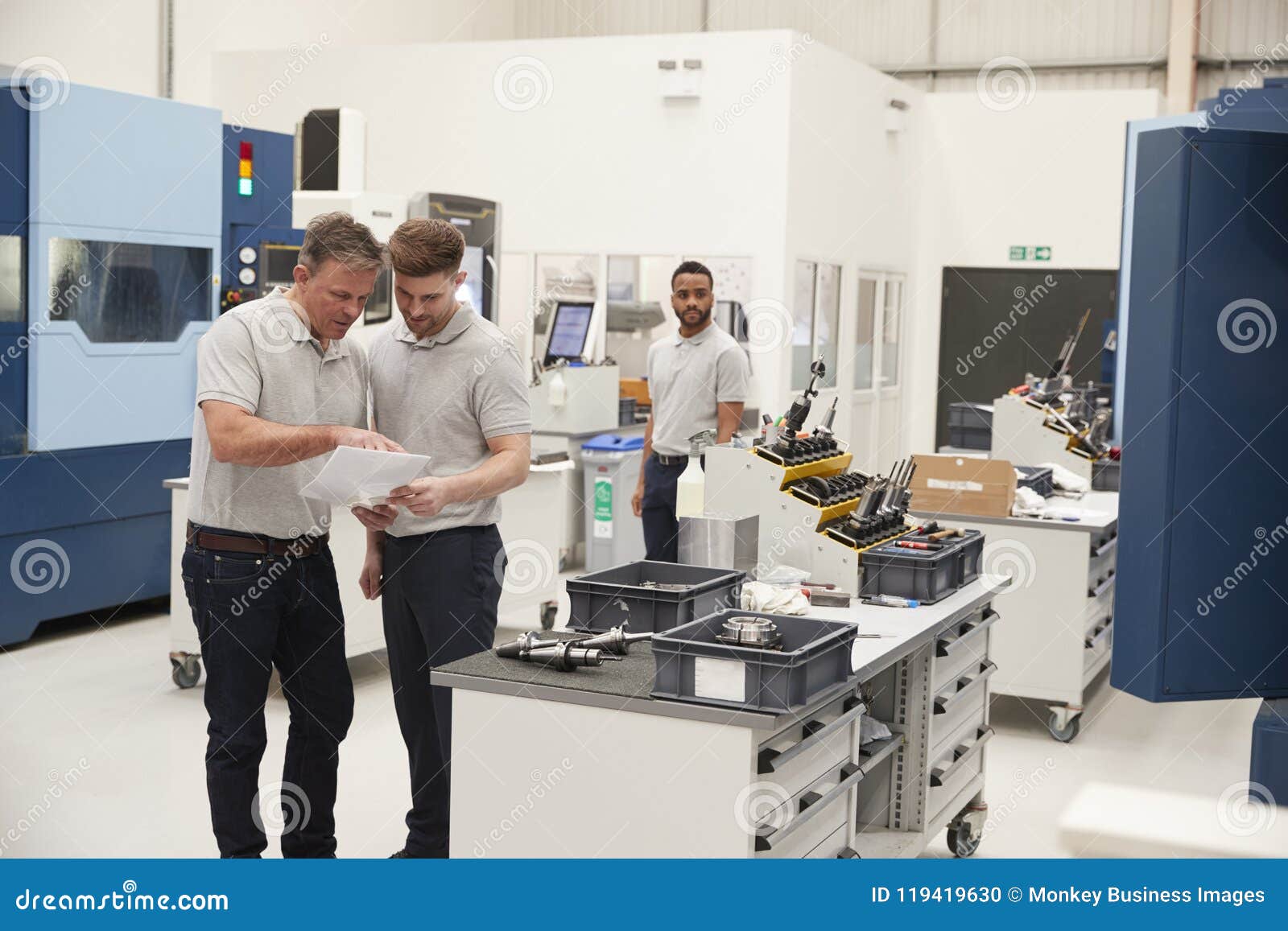 Engineer and Apprentice Meet on Floor of Engineering Workshop Stock
