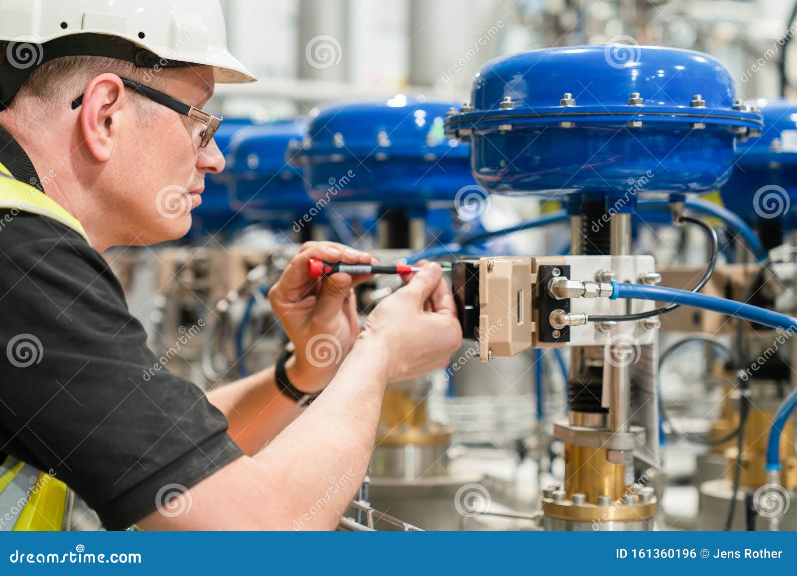 Engineer Checks an Pneumatic Valve with a Screwdriver Stock Photo