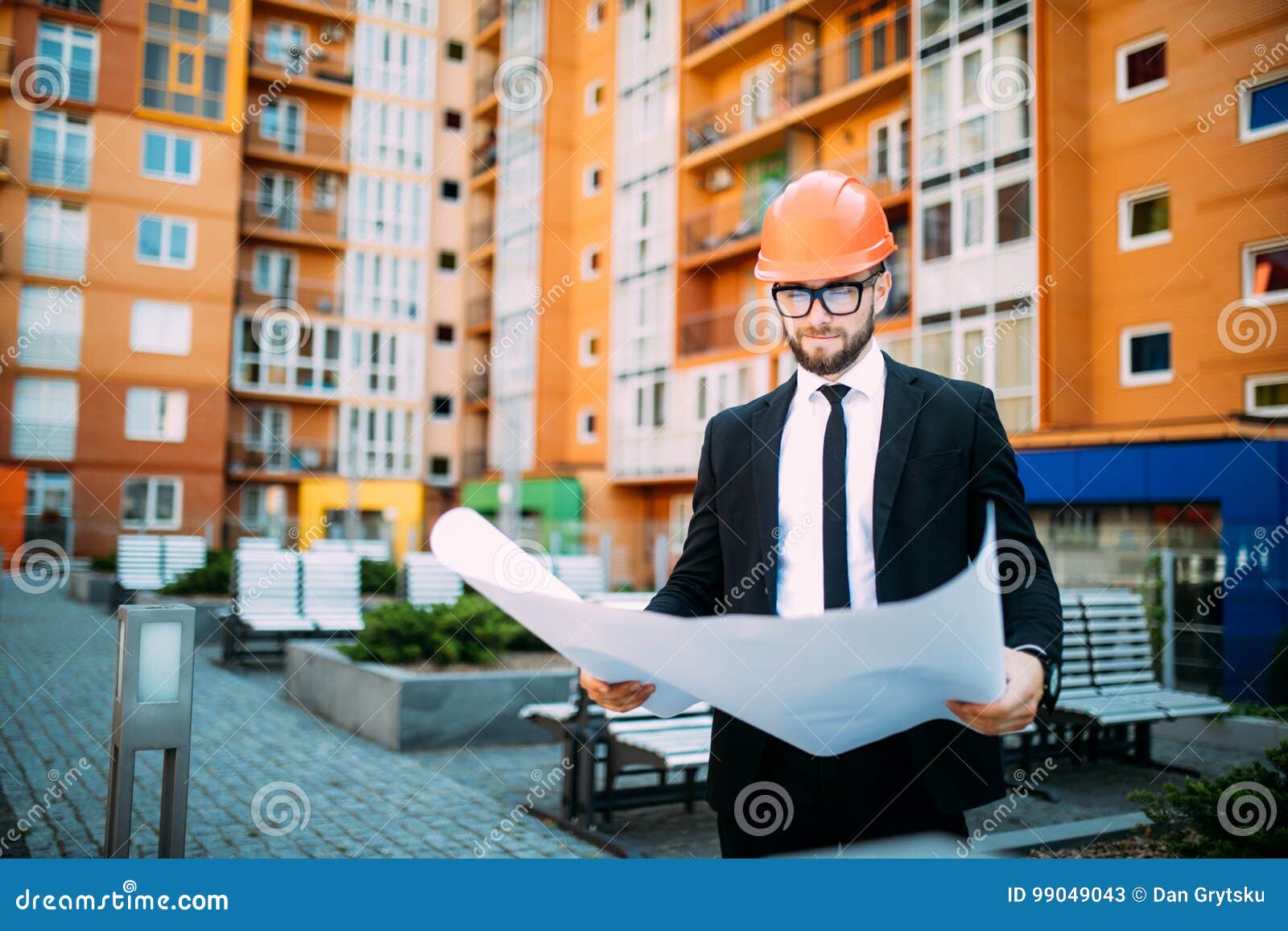 Engineer in Front of Modern Building with Plan Looking at Blueprint