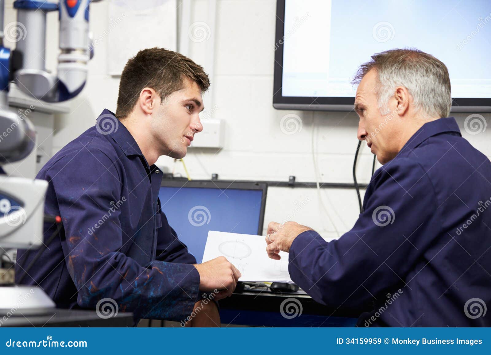 engineer showing trainee plans with cmm arm in foreground