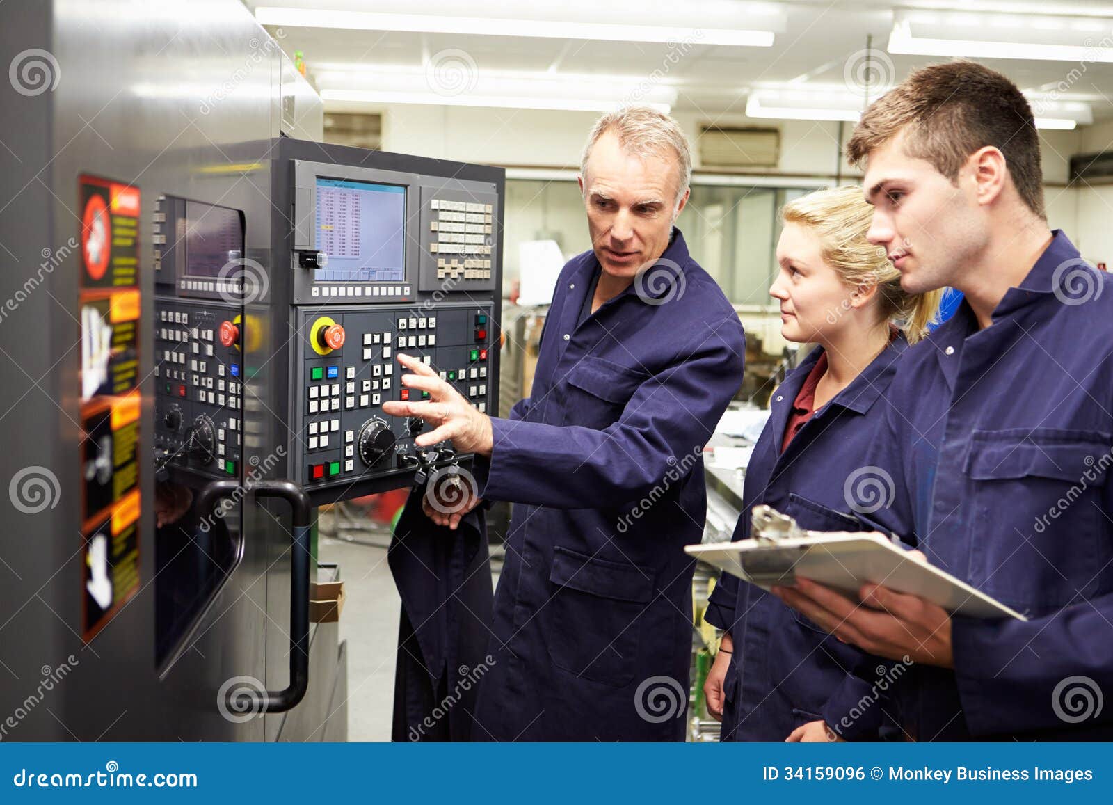 engineer teaching apprentices to use computerized lathe