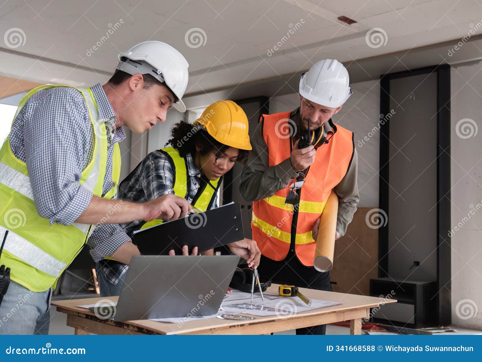 engineering team collaborates on work plan at construction site with safety gear and blueprints