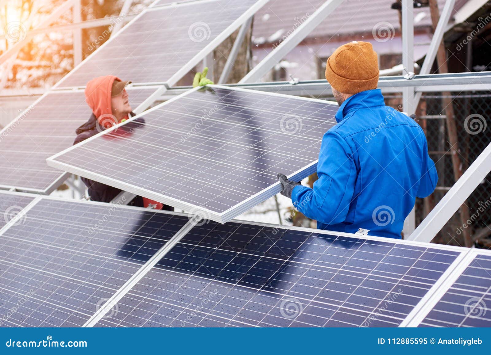 Photovoltaic panels on the roof with snow, with a snow shovel in