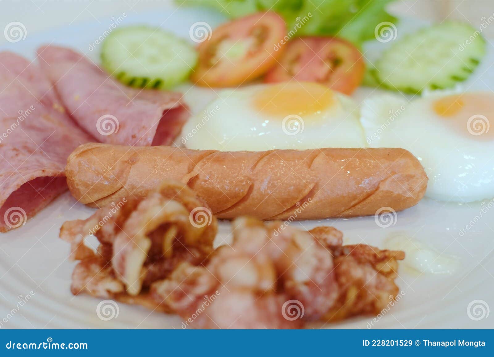 english breakfast, fried egg, tomatoes, bacon, sausage and cucumbe