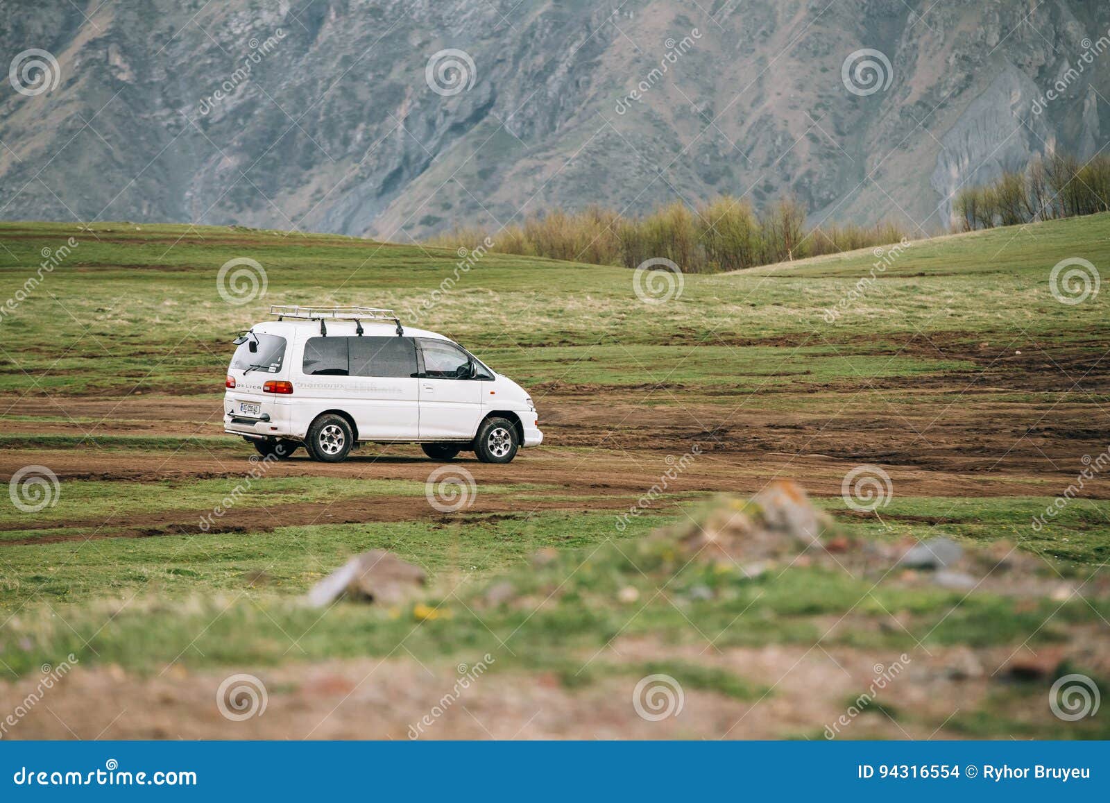 Engranaje del espacio de Mitsubishi Delica en del camino en el moun georgiano del verano. Stepantsminda Gergeti, Georgia - 23 de mayo de 2016: El engranaje del espacio de Mitsubishi Delica en la carretera nacional en montañas del verano ajardina Delica es una gama de camiones y de vehículos multiusos producidos por los motores de Mitsubishi