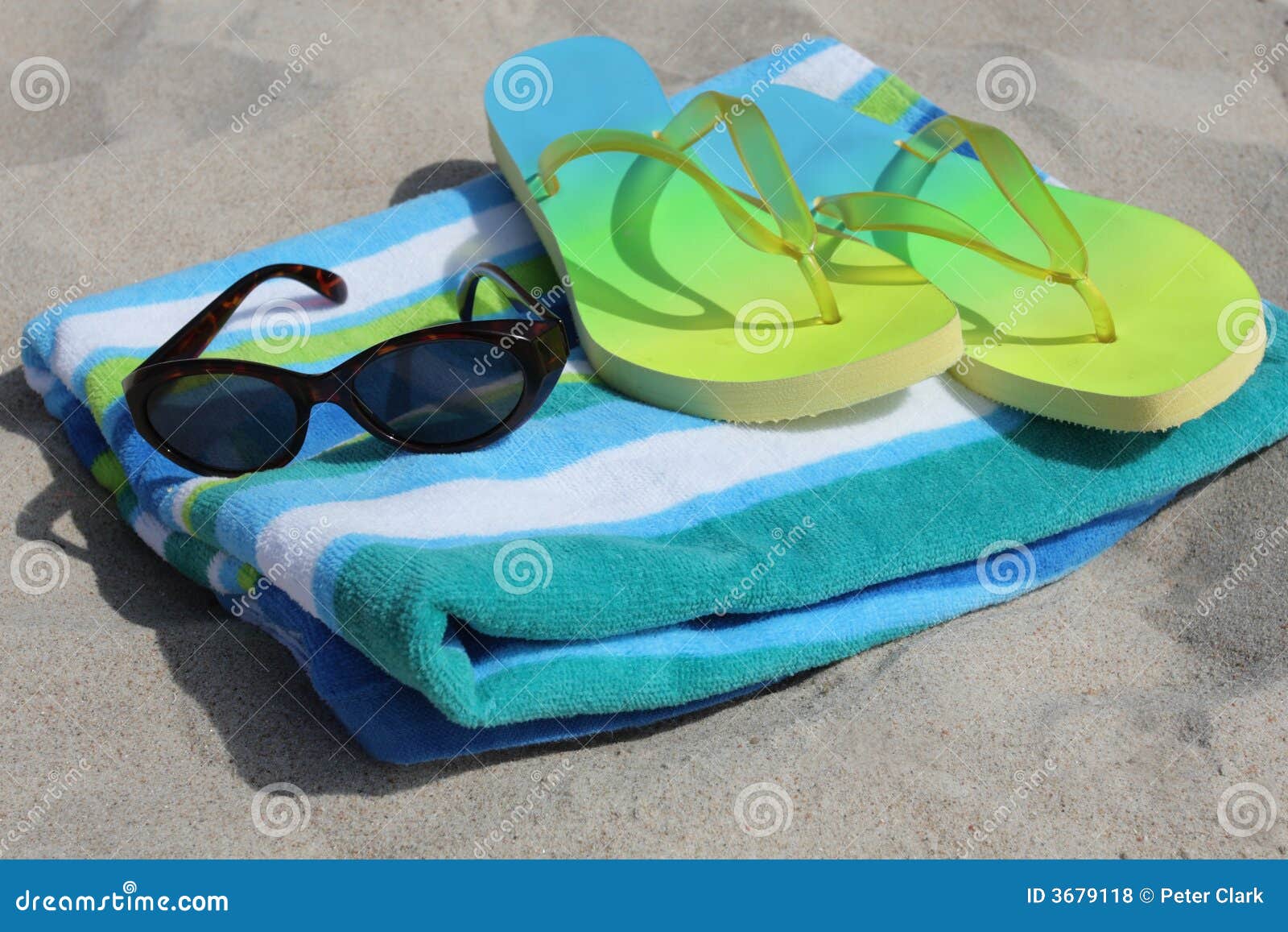 Engrenagem da praia. Flip-flops e óculos de sol em uma toalha na praia.