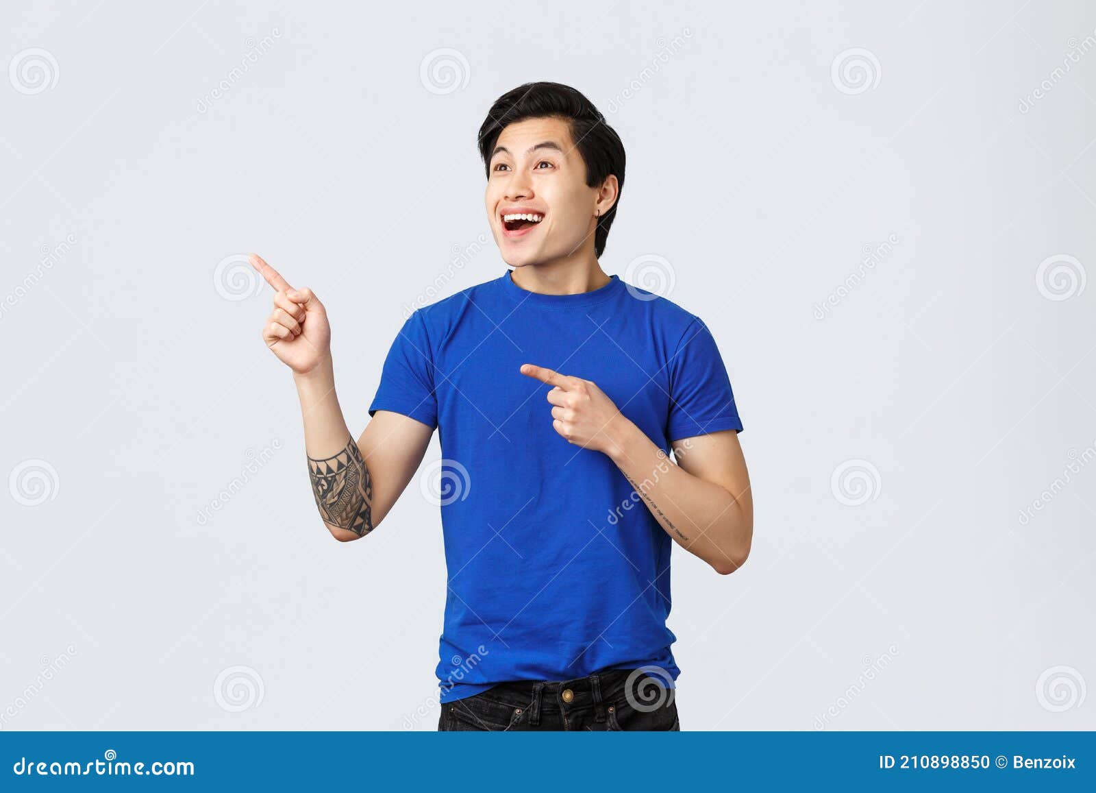 Enthusiastic And Happy Good Looking Asian Guy In Blue T Shirt Smiling Astonished And Amazed