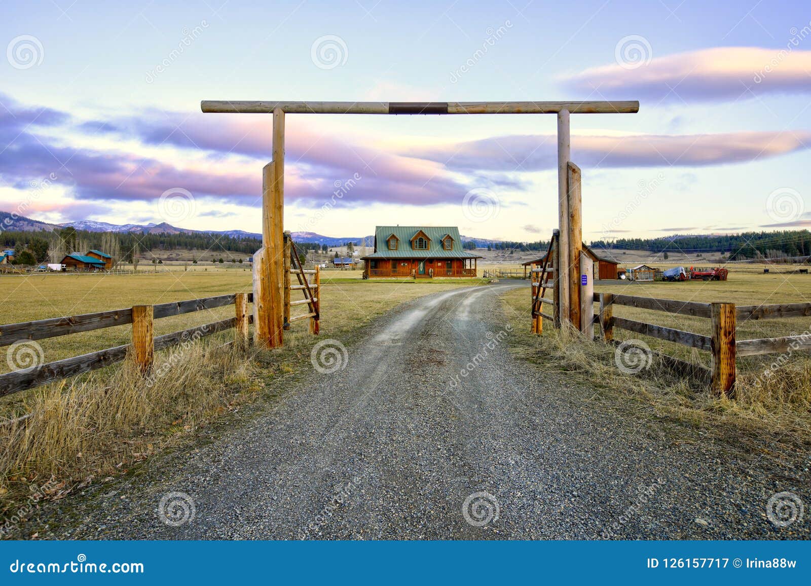 entry gate to a nice wooden ranch home with beautiful landscape.