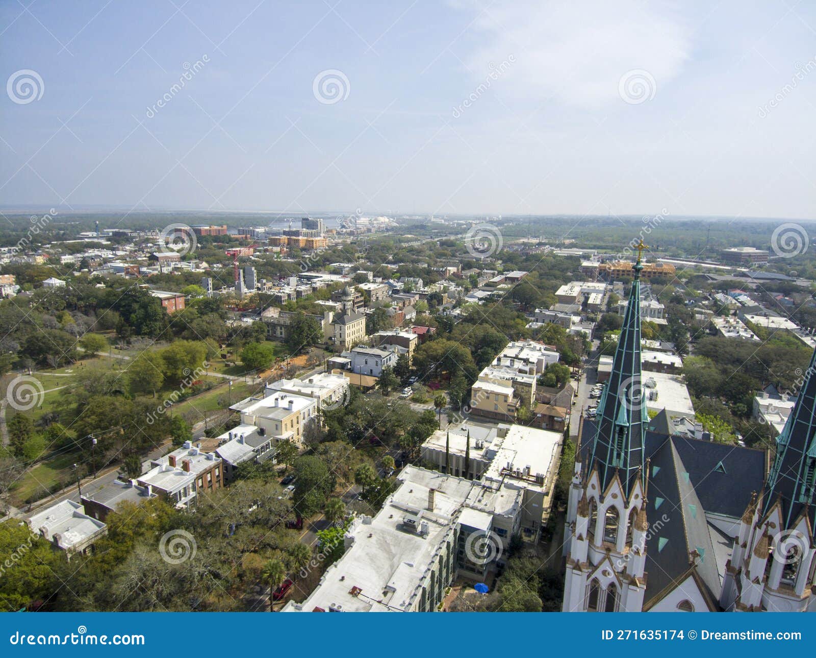 erial shot of the office buildings, apartments and shops in the city skyline surrounded by a river, lush green trees, roads and