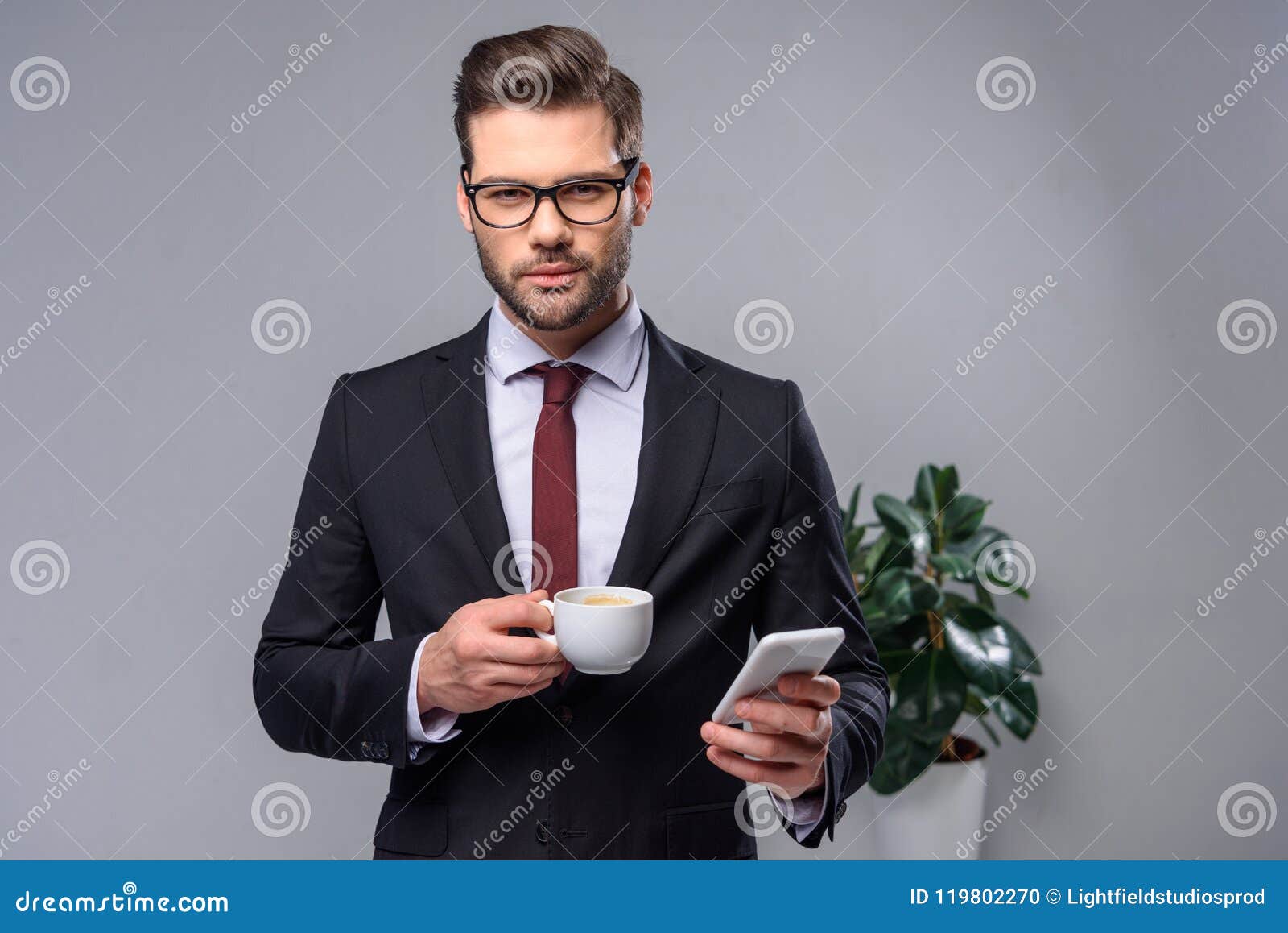 Ernstige smartphone van de zakenmanholding en kop van koffie en het bekijken camera