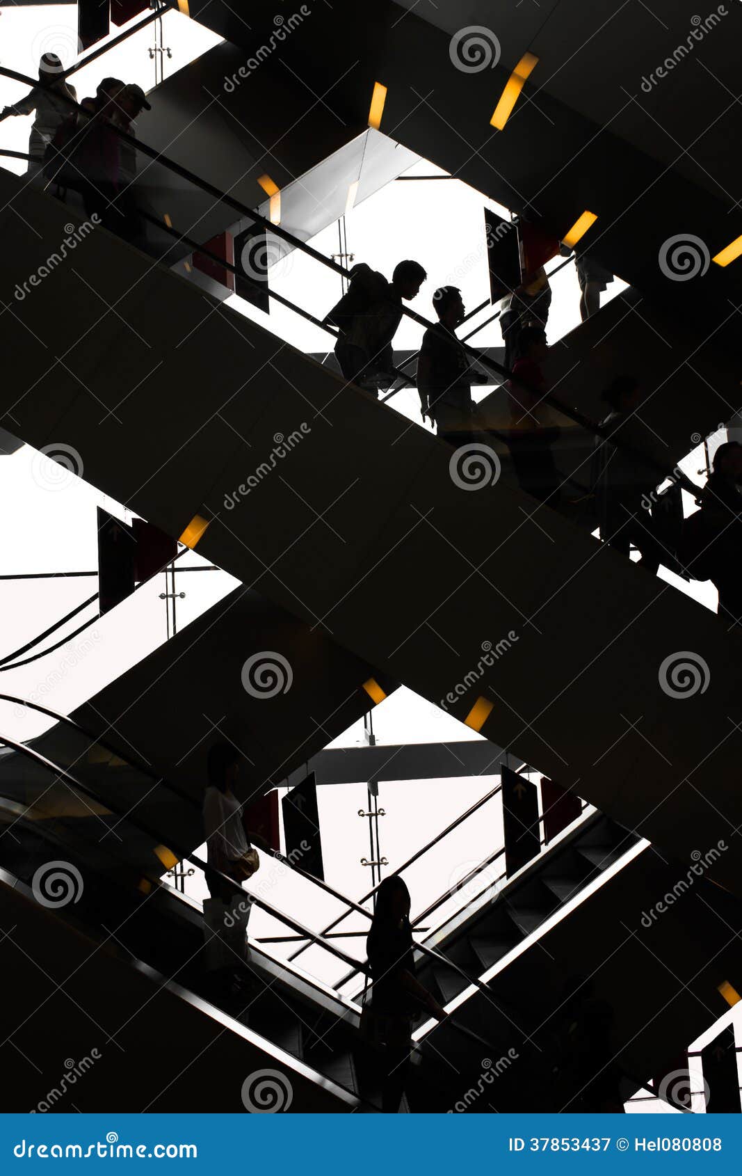 Escalator - black and white. Busy escalator with silhouettes of people in black and white with orange lights.