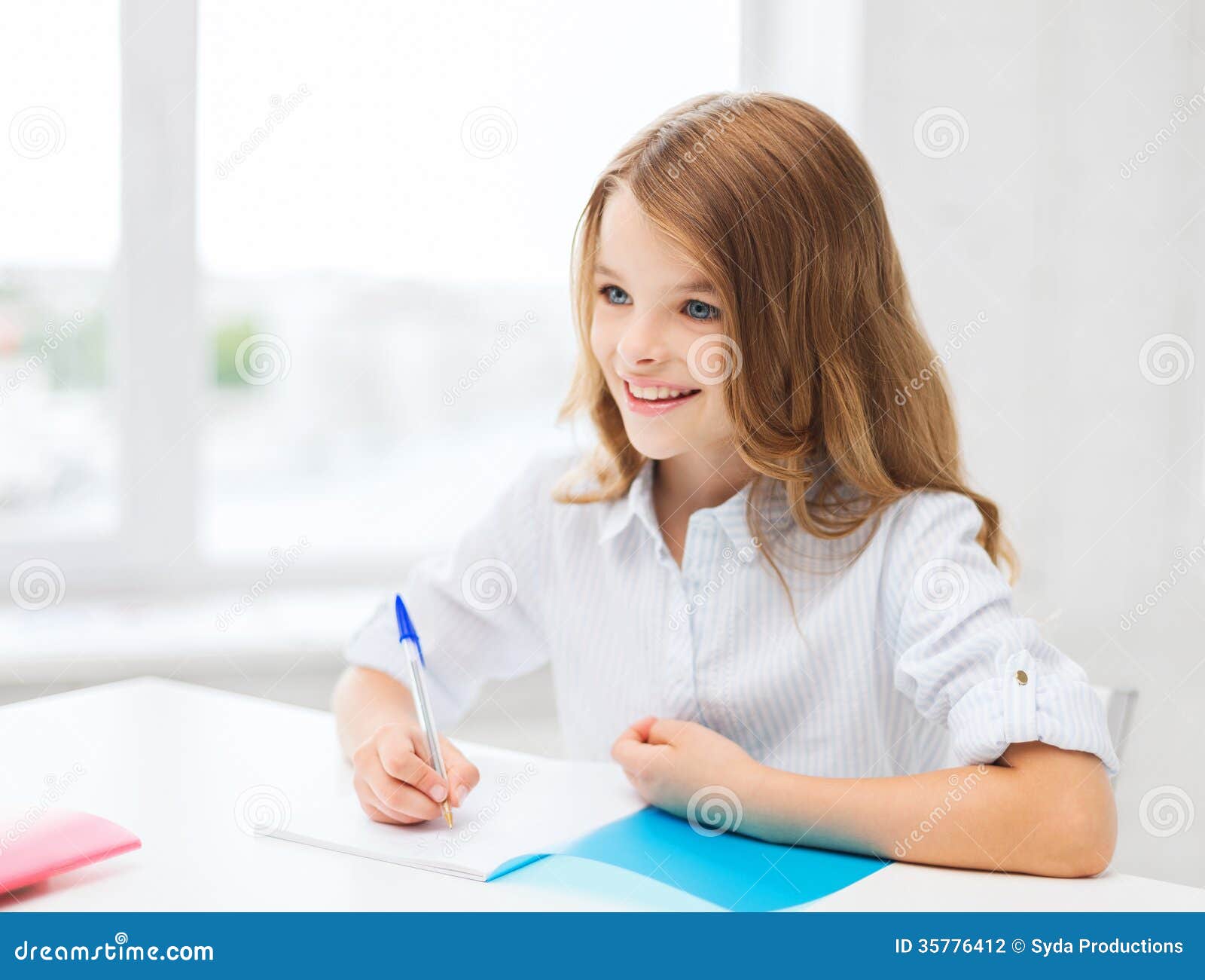 Educación y concepto de la escuela - pequeña escritura de la muchacha del estudiante en cuaderno en la escuela