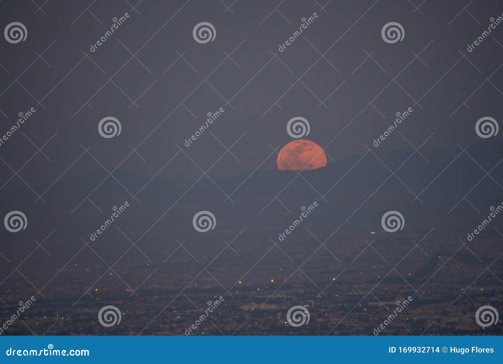 moon sphere peeking out from behind the mountains over the city