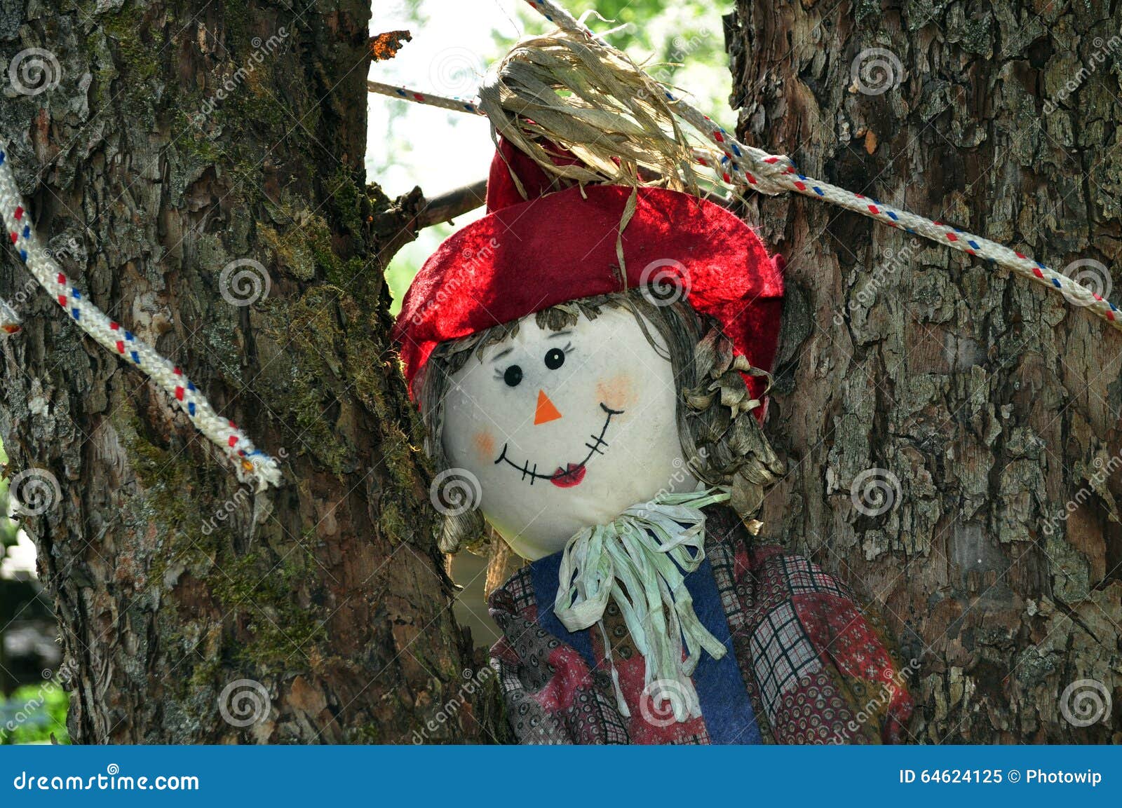 Espantapájaros de la diversión. Espantapájaros sonriente alegre en el árbol