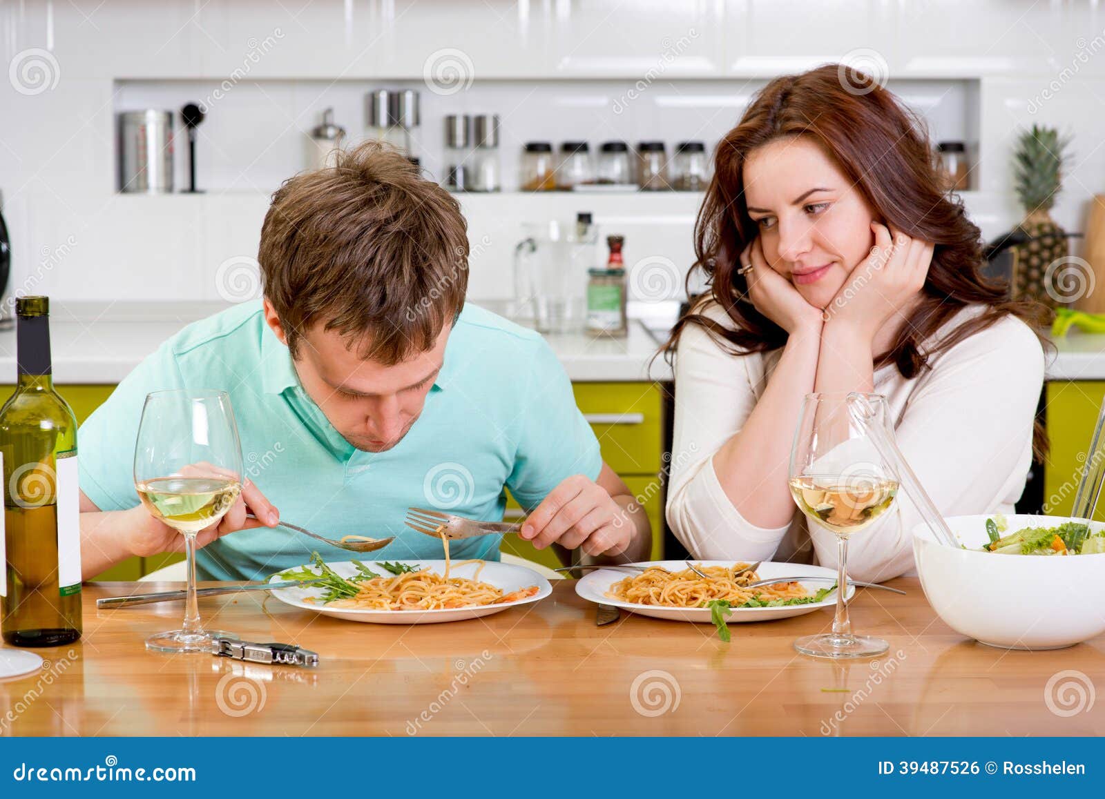 Пока жена готовит муж. Мужчина и женщина ужинают. Мужчина и женщина завтракают. Супруги за столом. Муж ужинает на кухне.