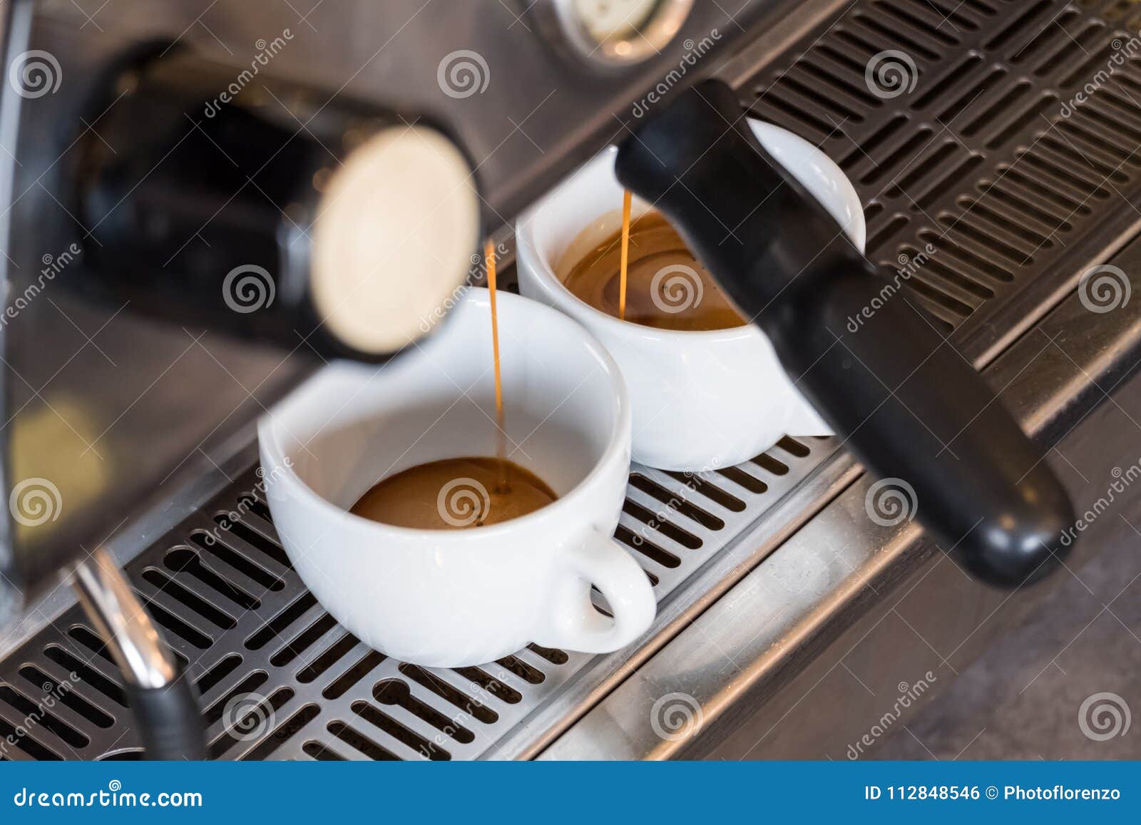 Espresso Dripping from Portafilter of Coffee Machine into White Stock
