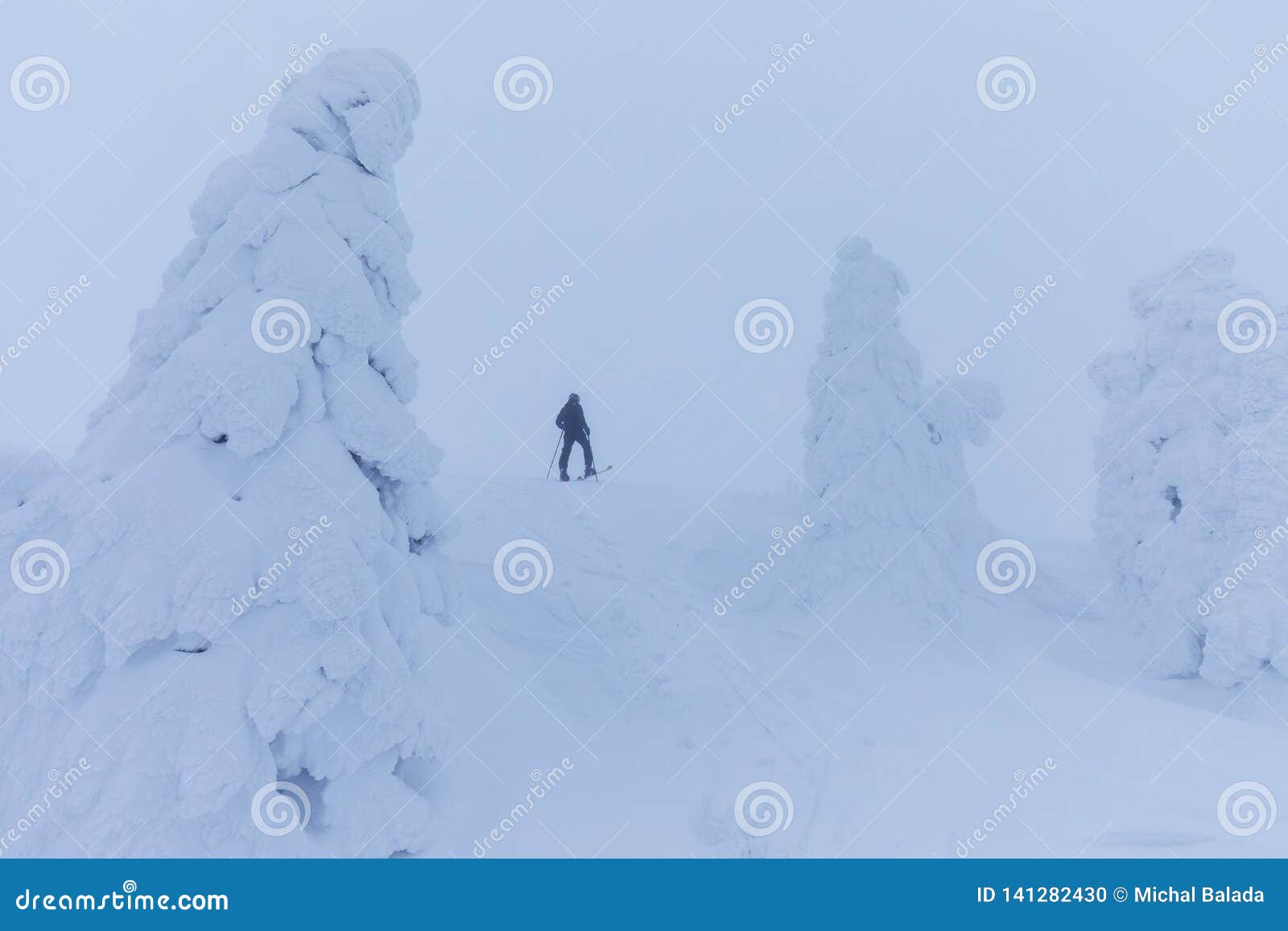 Esquiador de Backcountry que empuja a través de la niebla en una cuesta nevosa Esquí que viaja en condiciones del invierno crudo Tourer del esquí que se divierte adentro en las montañas Paisaje alpino del invierno y tiempo amplio de la Navidad del paisaje de la montaña Feliz Año Nuevo