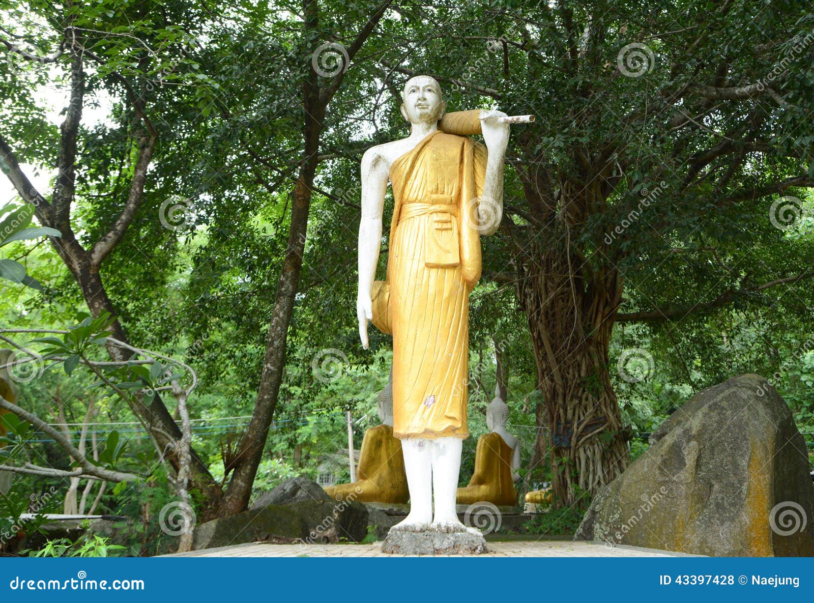 Estatua derecha del budda con el fondo grande del árbol