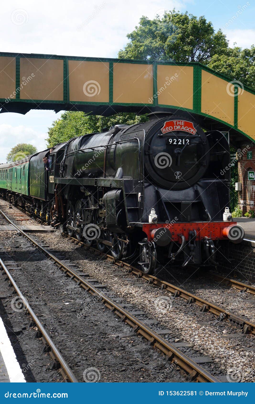 Estrada de ferro meados de do vapor de Hants. Ropley, Alresford/Reino Unido - 27 de maio de 2019: Uma foto de um trem do vapor como passa sob uma ponte e incorpora a estação de Ropley