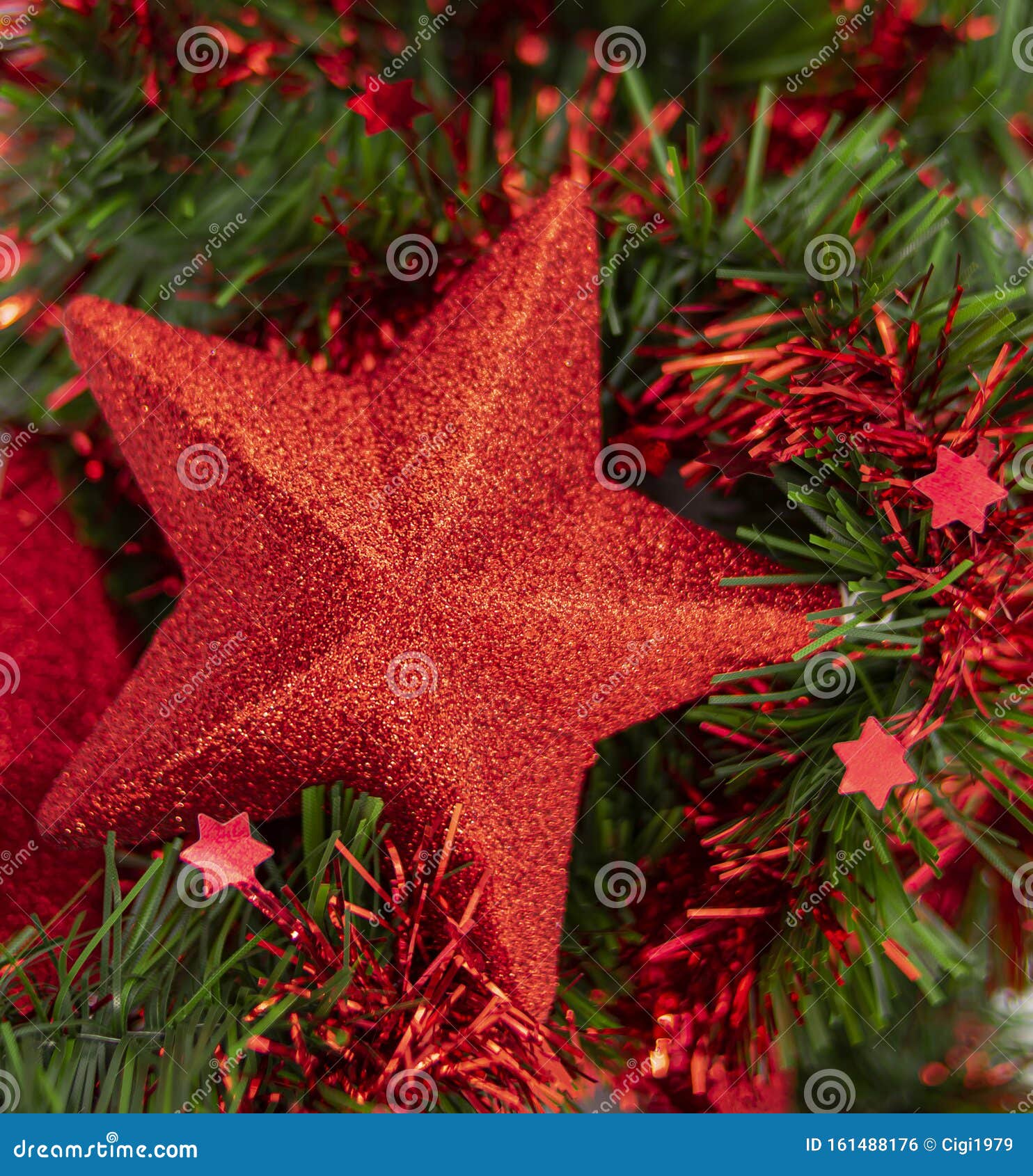 shiny decorative christmas star on green and red tinsel leaves