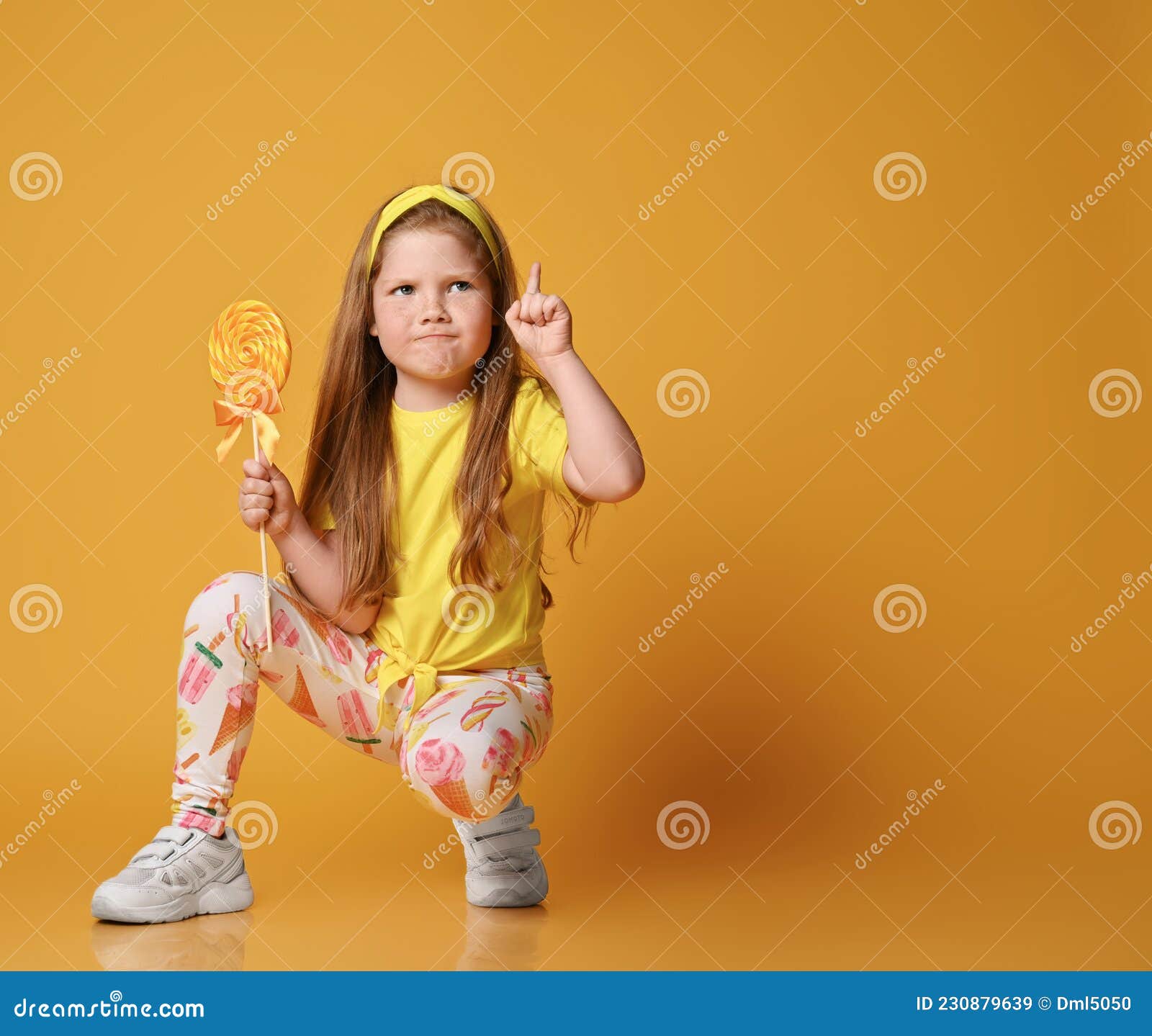 Una niña alegre con una camiseta amarilla se sienta en el suelo