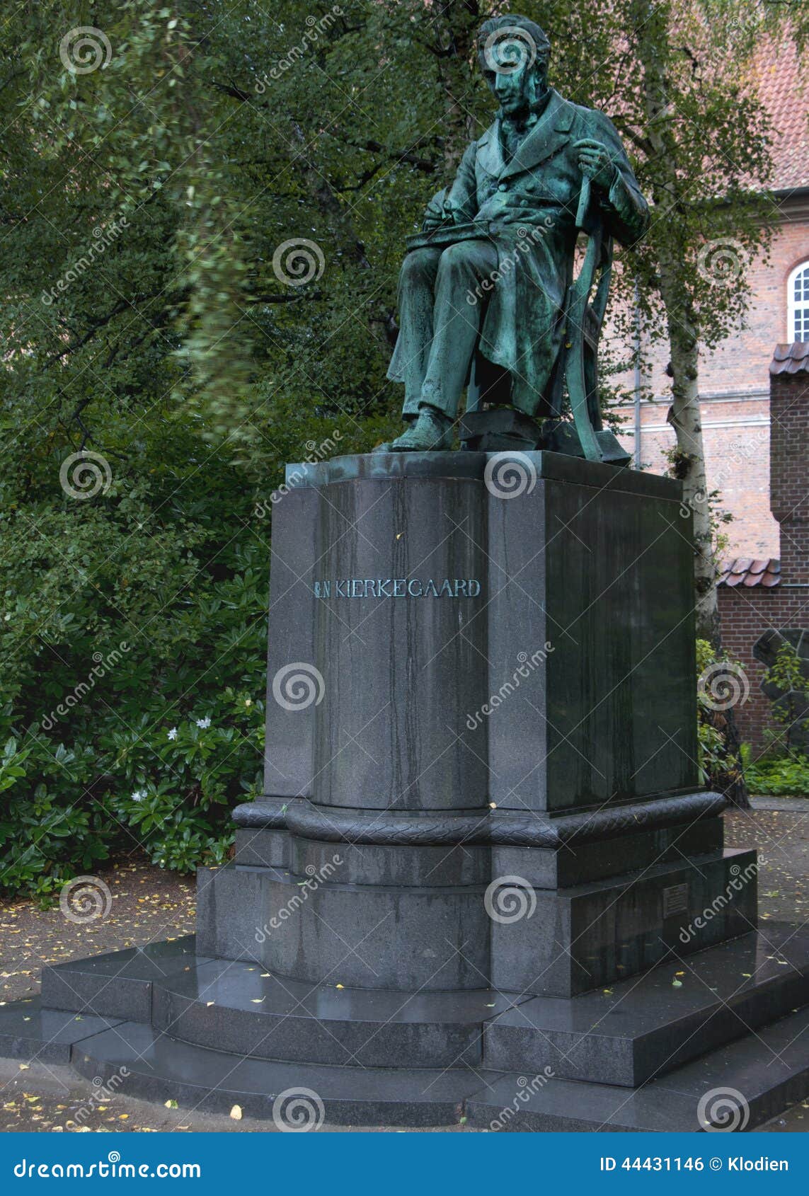 Estátua de Soren Kierkegaard em Copenhaga, Dinamarca. COPENHAGA, DINAMARCA - CERCA DO SETEMBRO DE 2010: A estátua de Soren Kierkegaard girou o verde e esconda no verde de um parque É o primeiros filósofo do existencialista e poeta e autor do século XIX