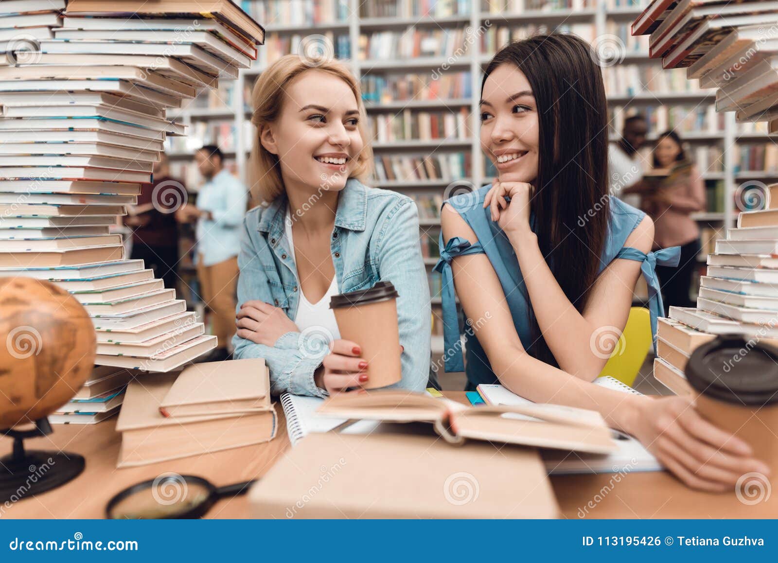 Ethnic Asian Girl and White Girl Surrounded by Books in Library