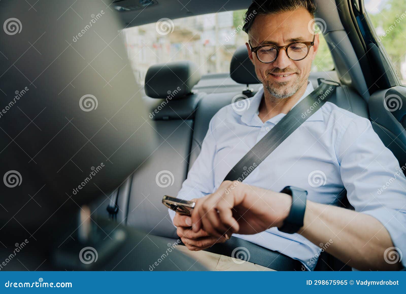 European Grey Man Looking at Smartwtch and Using Mobile Phone at Car
