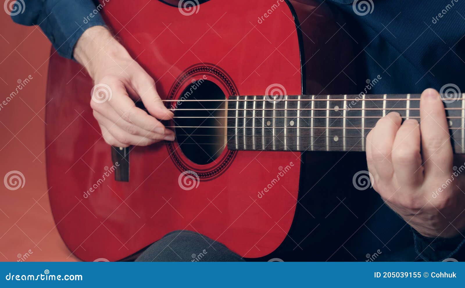 european man plays an red acoustic guitar