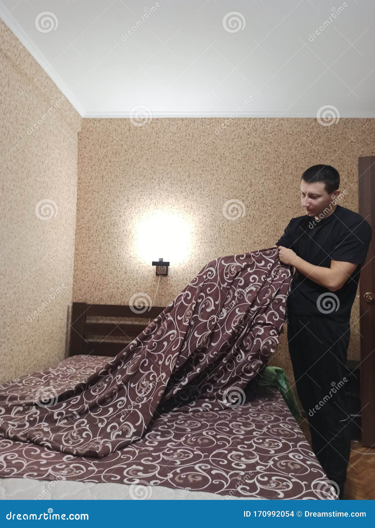 European Man Put Duvet Cover On Blanket In Bedroom Stock Photo