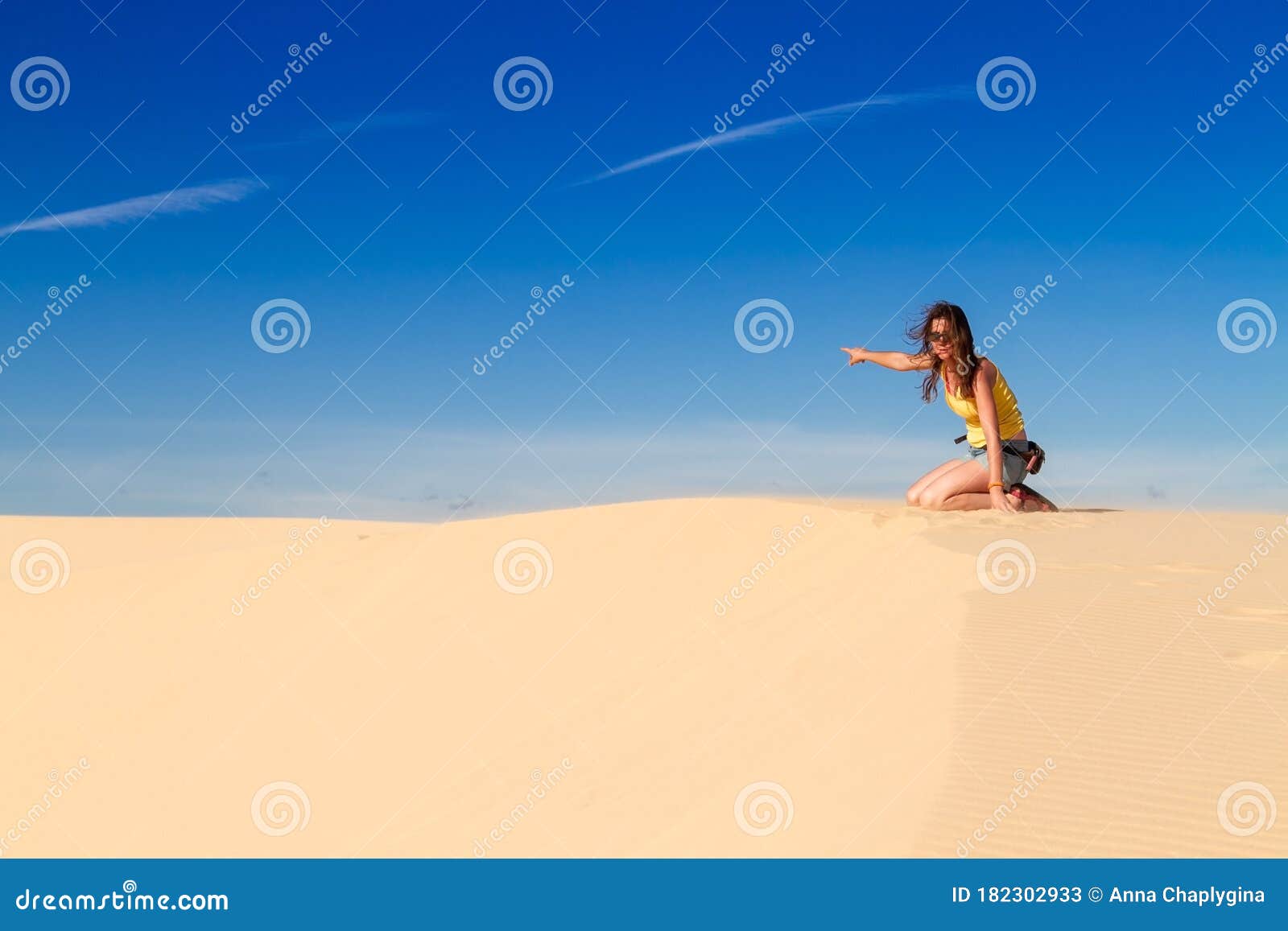 European Woman Sitting on the Crest of a Dune and Pointing into the ...