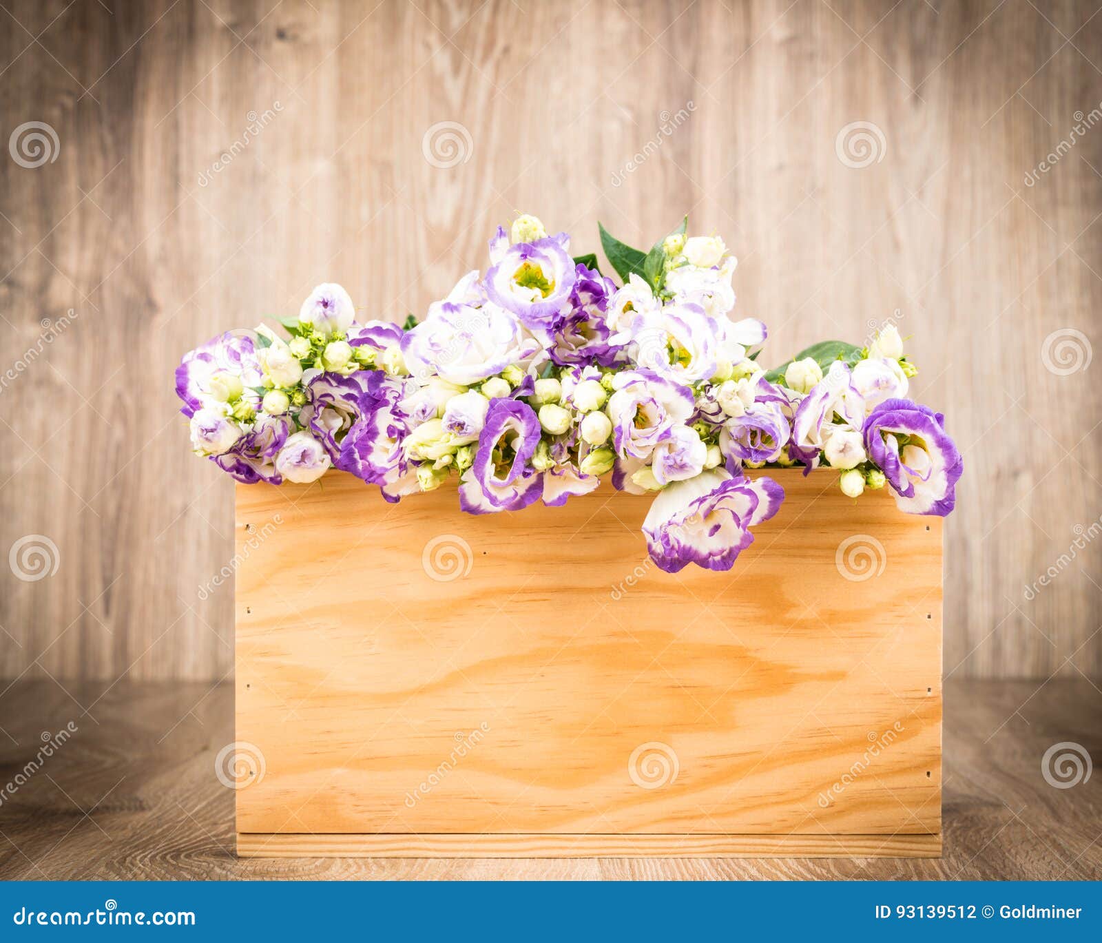 Photo of a box of Eustoma flowers on wooden background