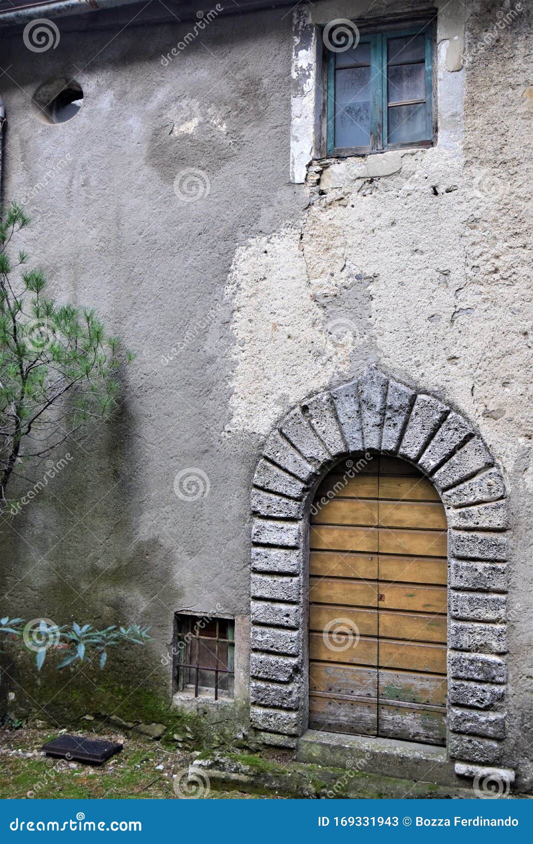 evocative image, veiled by time, of the wall with stone arch and wooden door of an old house, in vergemoli.