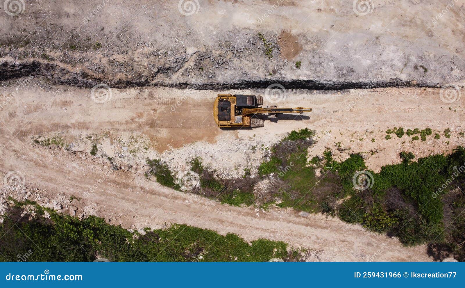 an excavator travelling on unpaved road corner aerial photo
