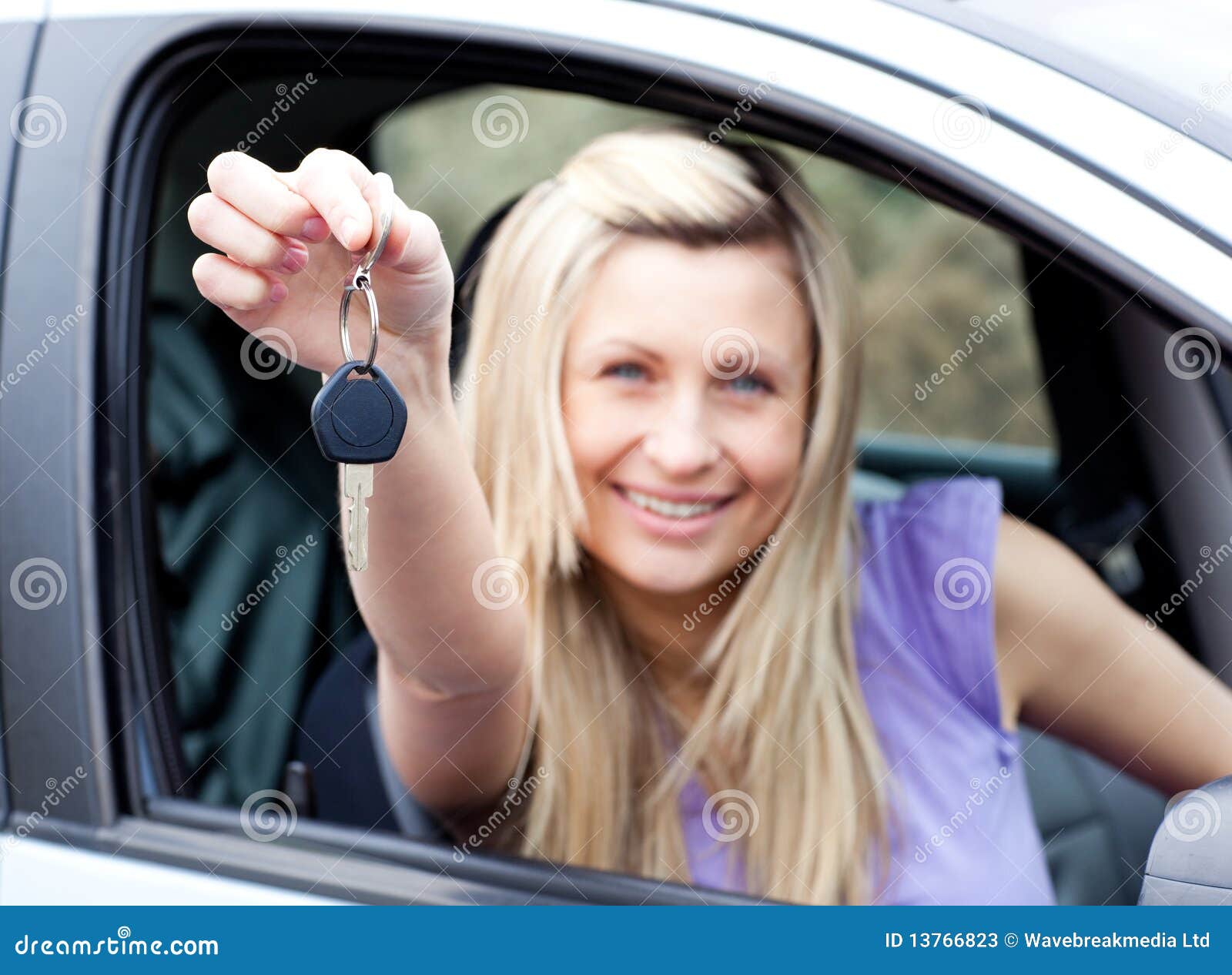 Retrato de um excitador novo entusiástico que prende uma chave após ter comprado um carro novo