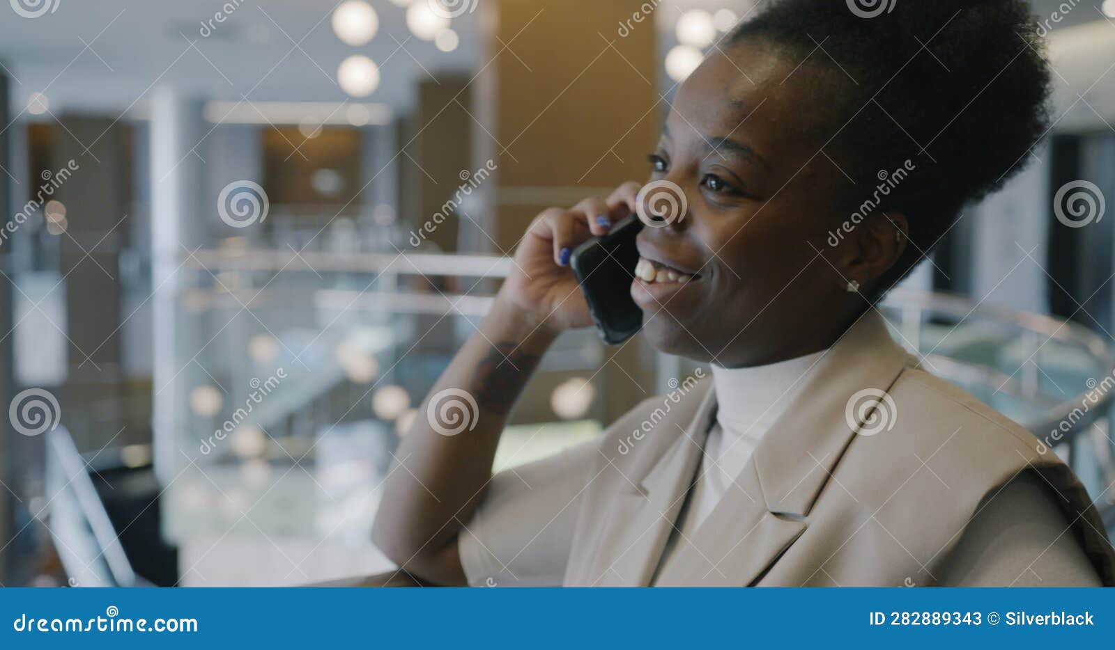 Excited African American Businesswoman Chatting On Mobile Phone And Smiling In Iluminated Hotel