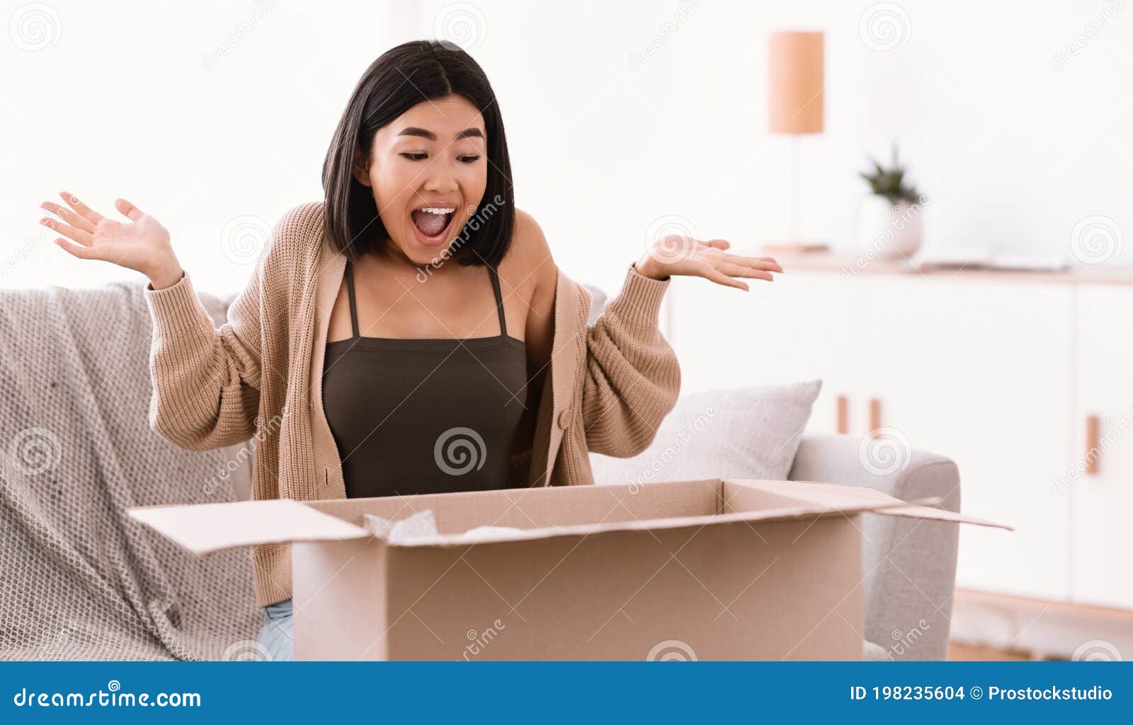 excited asian woman unpacking parcel after online shopping