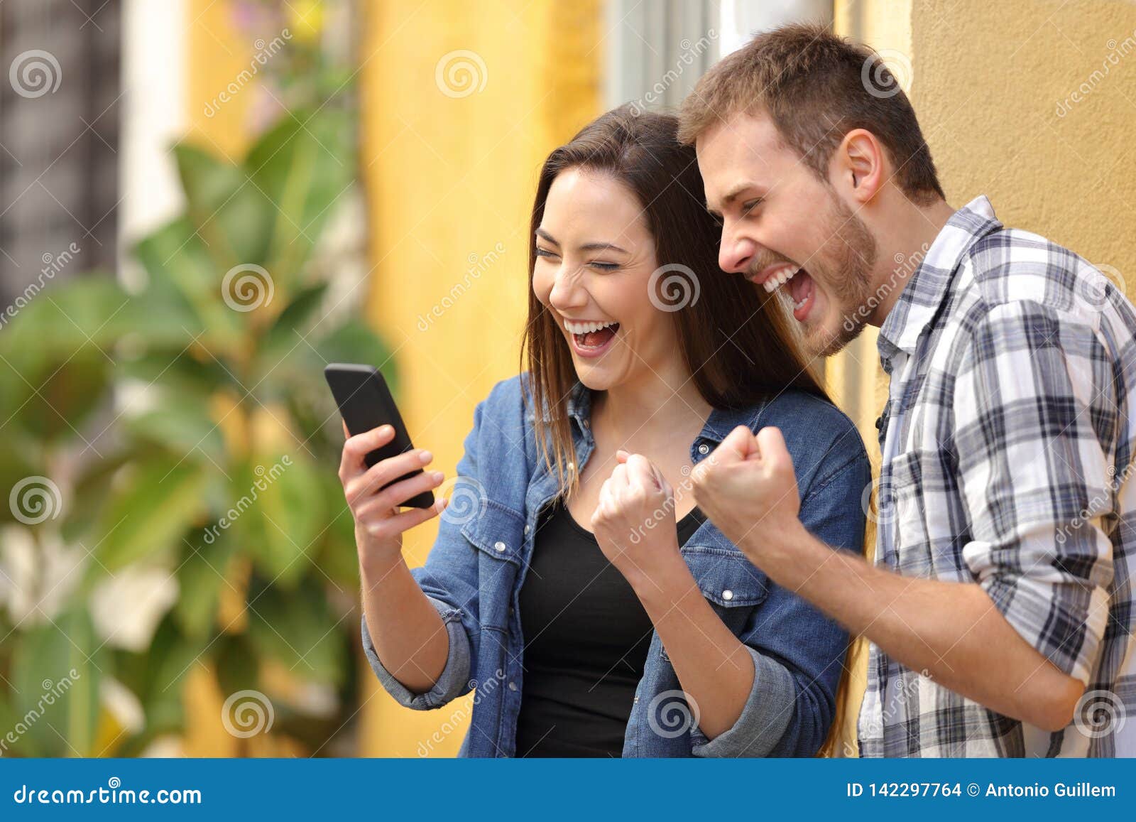 excited couple finding online offers on phone in the street