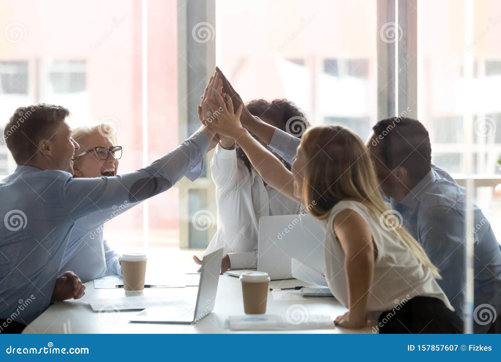 excited diverse colleagues give high five at meeting
