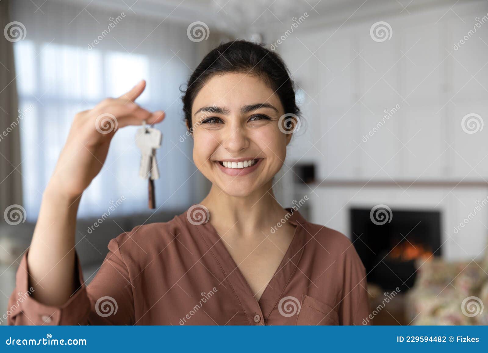 excited indian female become homeowner look at camera hold key