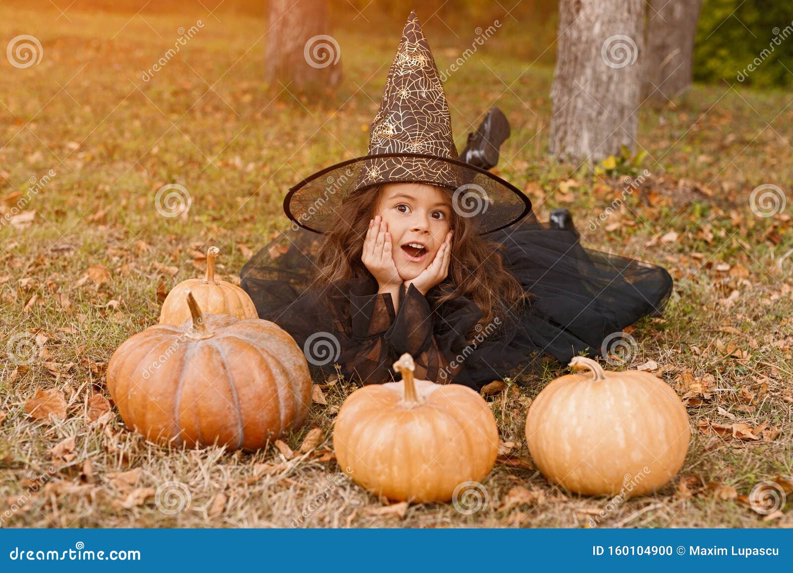 Cute Girl in Witch Costume Lying with Pumpkins Stock Photo - Image of ...