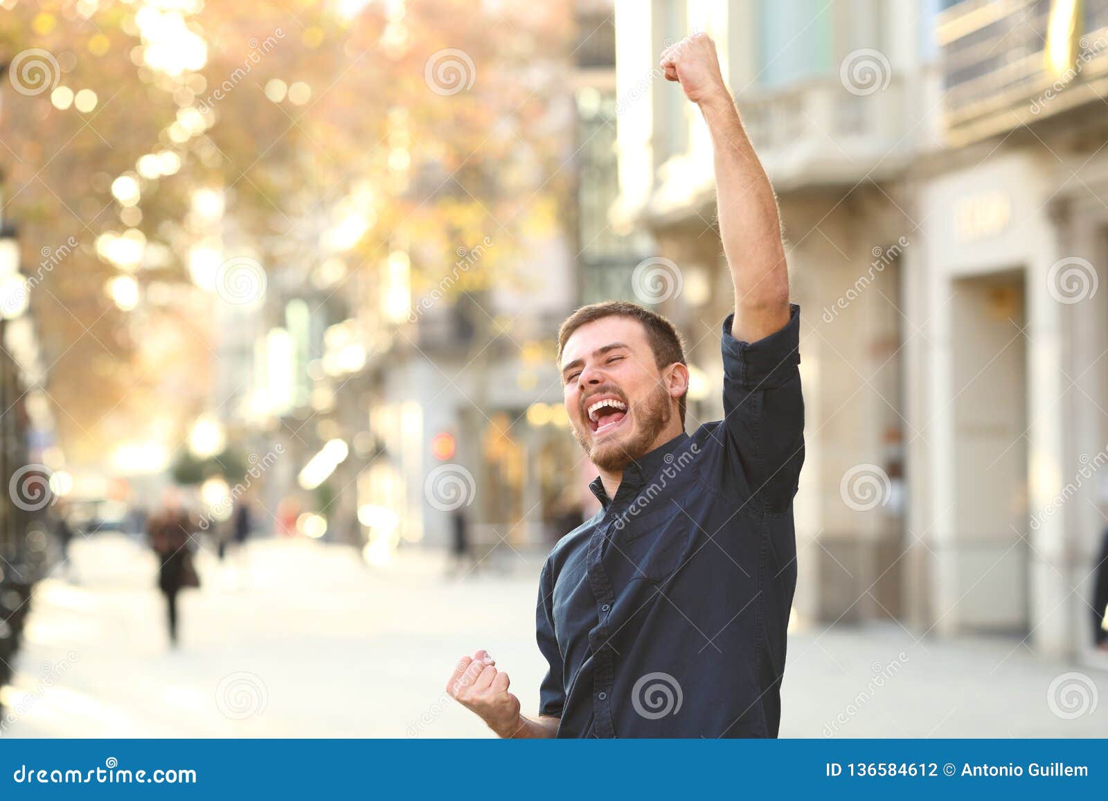 excited man raising arms celebrating sucess