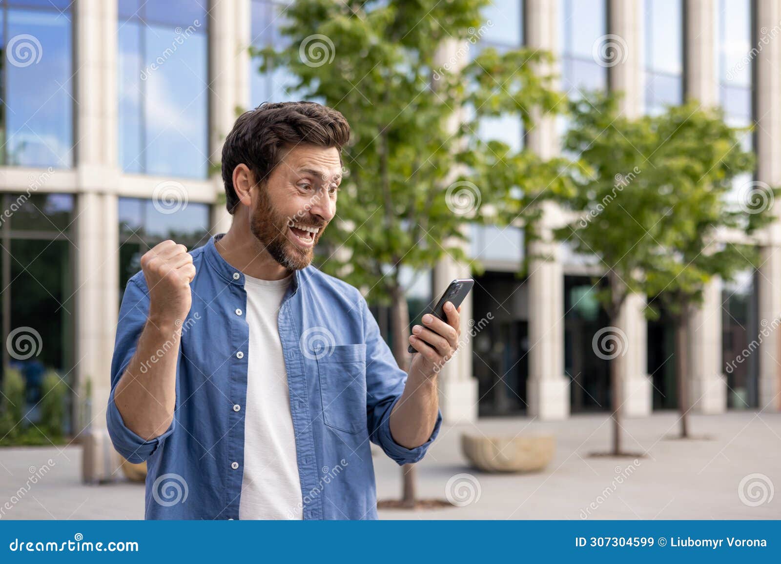 Joyful Bearded Businessman Celebrating Success with Smartphone Outside ...