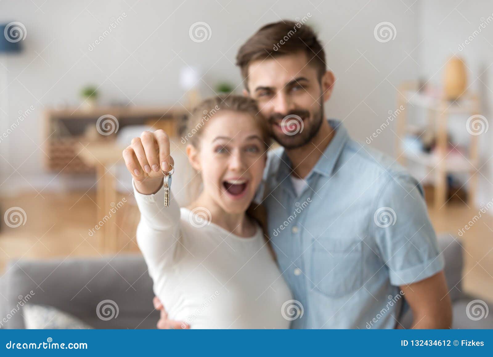 excited millennial couple holding key to new house