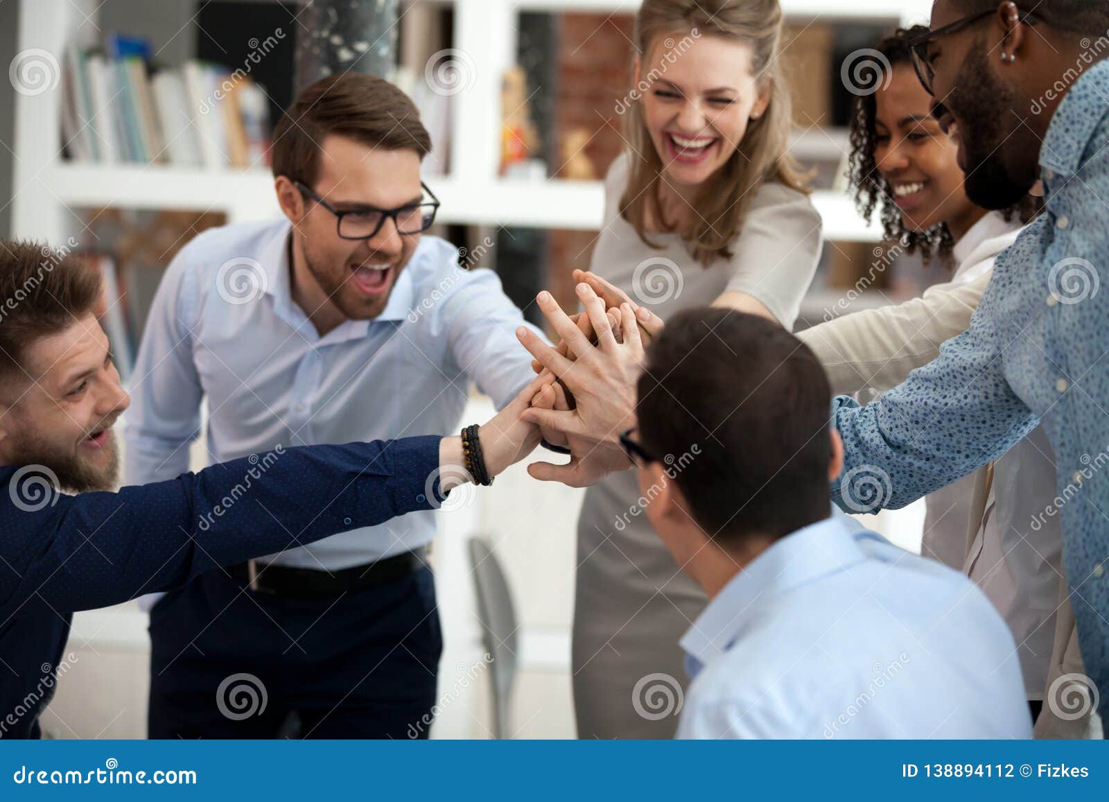 excited motivated multi-ethnic team people give high five in office