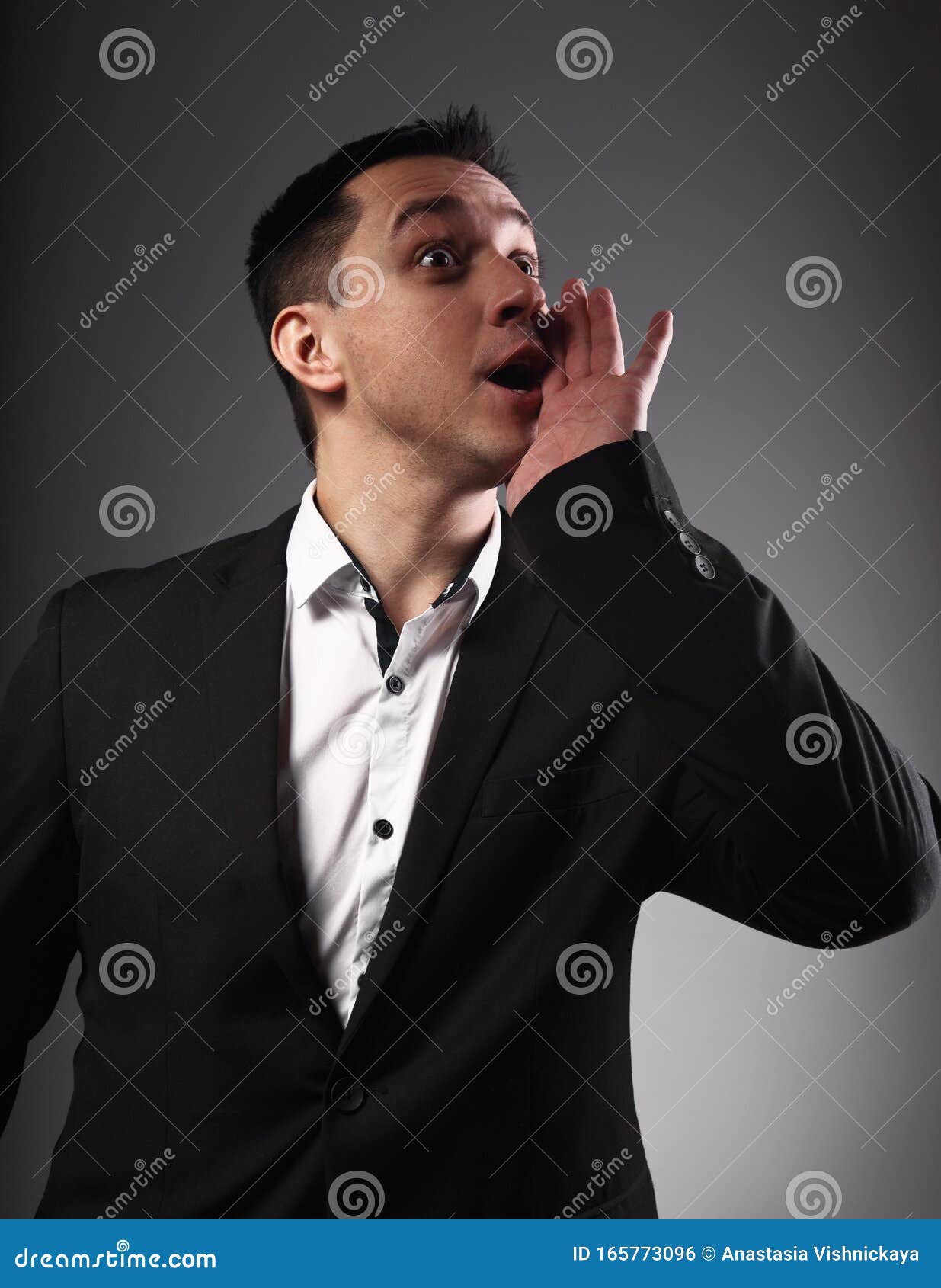 excited shouting young business man gesturing the hands loudspeaker sign in celebrating emotion with wide open mouth to agitate on