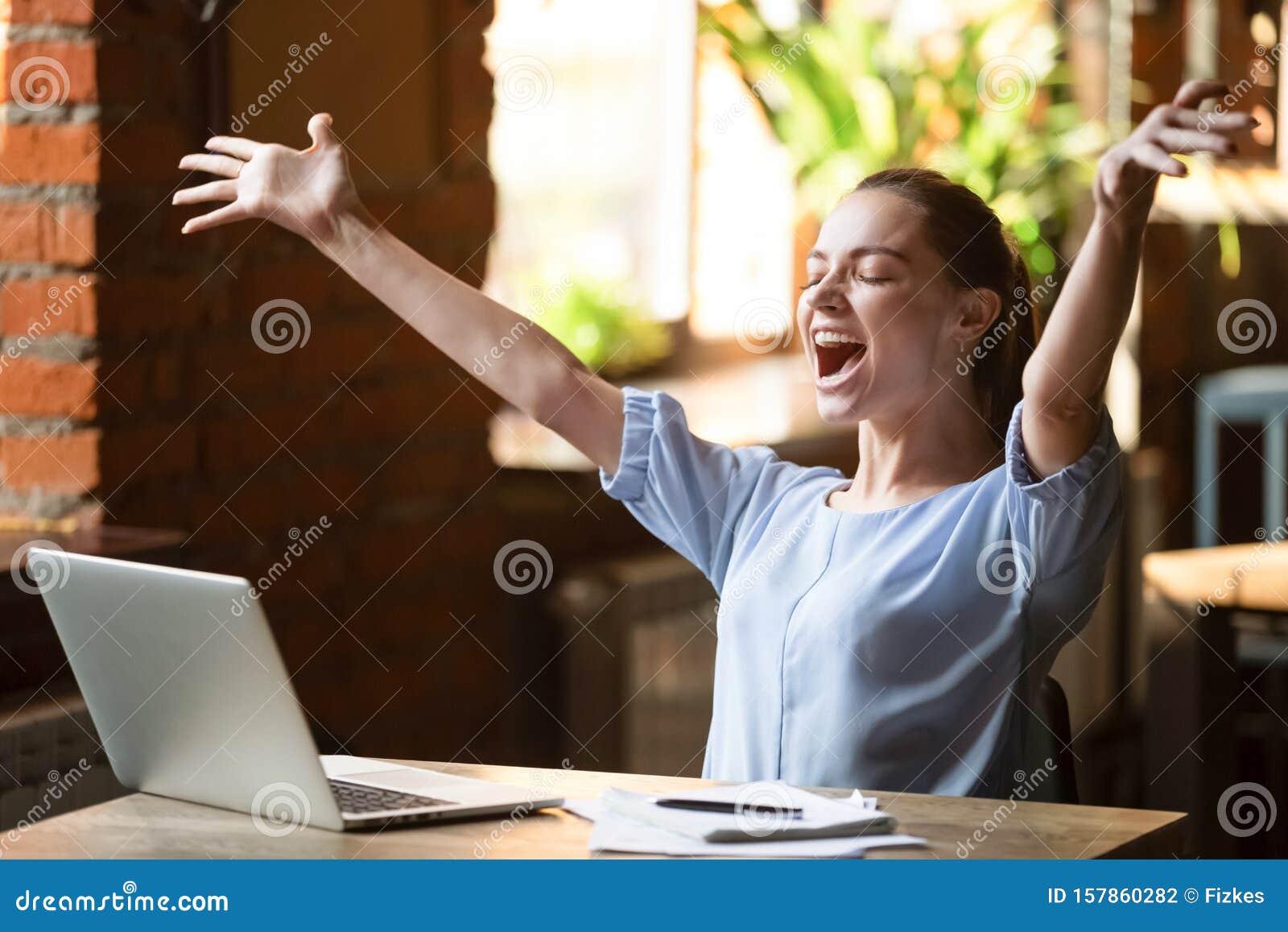 excited smiling woman celebrating online win, using laptop in cafe