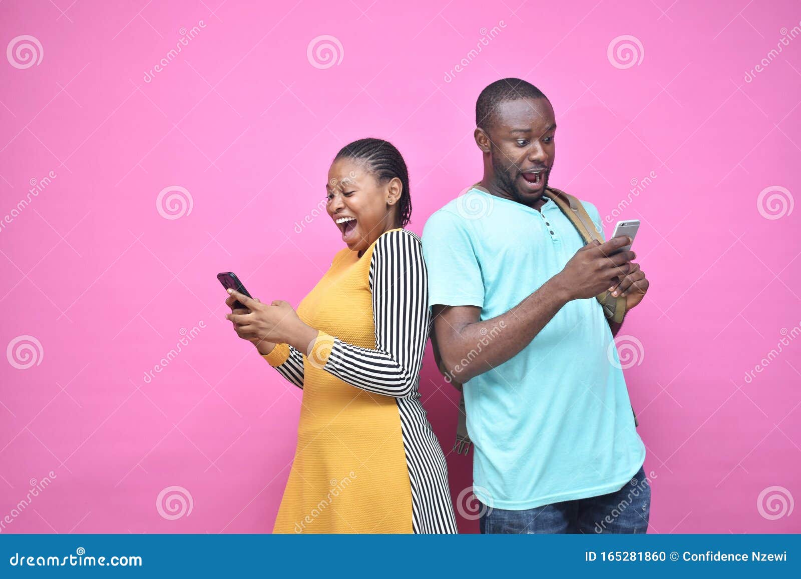 excited young black people standing back to back viewing contents on their phones, looking surprised, young african man and woman