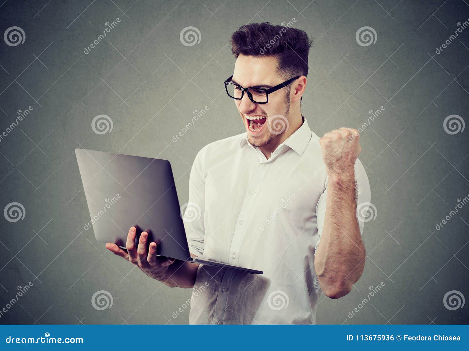 excited man with laptop computer celebrating success