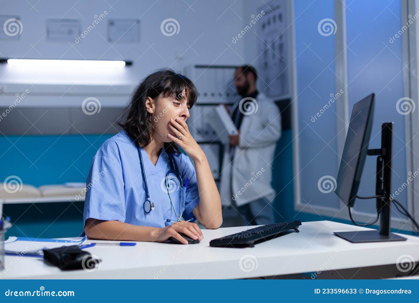 Exhausted Nurse Using Computer on Desk while Falling Asleep Stock Image